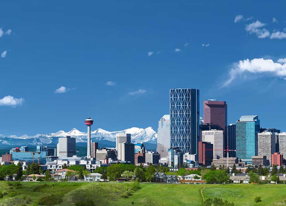 Photo of Calgary skyline with mountains in the distance.